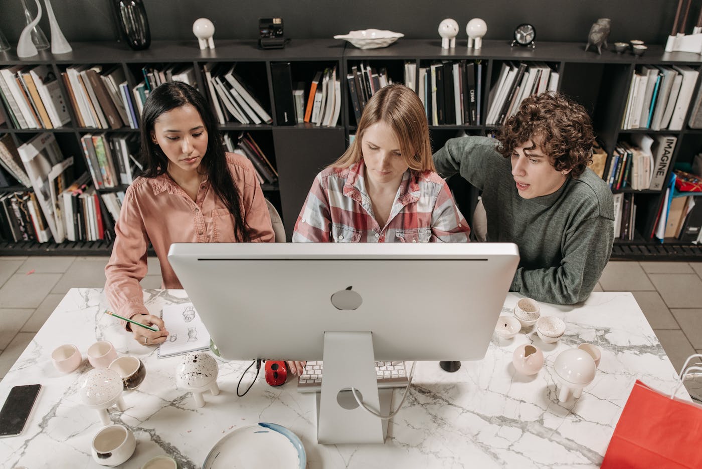 Technology professionals collaborating around a large desktop workstation.